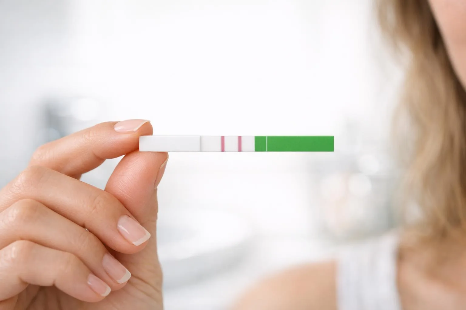 Kobieta trzyma test owulacyjny LH - dokładna metoda wykrywania dni płodnych